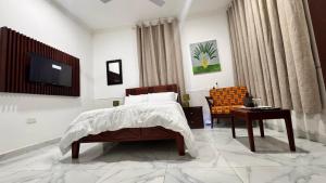 a bedroom with a bed and a tv and a table at Da Palm boutique resort in Aburi