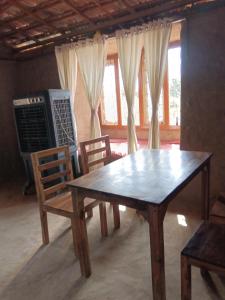 a wooden table and chairs in a room with windows at Ishika Homestay in Maheshwar