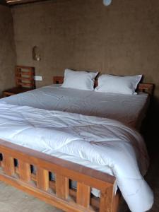 a large bed with white sheets and pillows at Ishika Homestay in Maheshwar