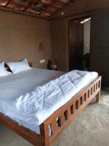 a bedroom with a large bed with white sheets at Ishika Homestay in Maheshwar
