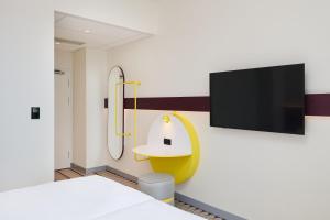 a room with a shower and a tv on a wall at Prize by Radisson, Wroclaw Sky Tower in Wrocław