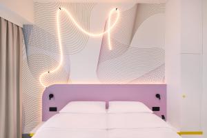 a bedroom with a white bed with a purple headboard at Prize by Radisson, Wroclaw Sky Tower in Wrocław