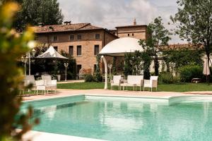 a pool with chairs and a gazebo and a building at Villa Mirandola in Mirandola