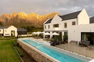 a resort with a pool and mountains in the background at Kleine Banhoek Manor in Stellenbosch