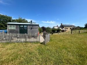 a small house in a field behind a fence at Astwell Mill Luxury Shepherds Hut in Helmdon