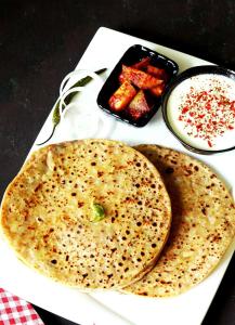 a white plate topped with two naan bread and dips at Grand Tree Hotel Shree Guru in New Delhi