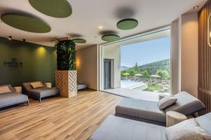 a living room with couches and a large window at Cavallino Experience - Alpine Wellness Hotel in Rumo