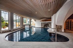 an indoor pool in a house with a large ceiling at Cavallino Experience - Alpine Wellness Hotel in Rumo
