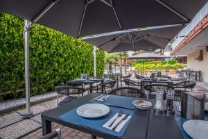 an outdoor patio with tables and chairs and umbrellas at Hotel Al Sole in Grado