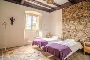 two beds in a room with a stone wall at Les Eres de Guardiolans in Vilada