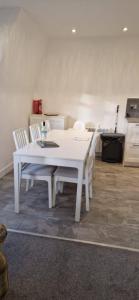 a white dining table and chairs in a kitchen at Wee Cumbrae View in Millport +4 photos