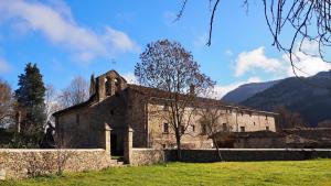 an old stone church in a field with mountains in the background at Les Eres de Guardiolans in Vilada
