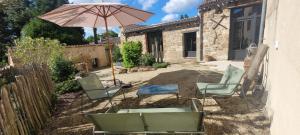 a patio with two chairs and an umbrella at Aumônerie du Prieuré in Pouzauges