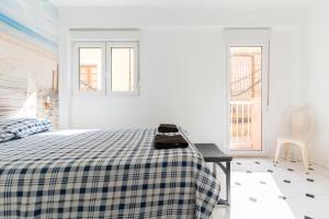 a white bedroom with a bed with a checked blanket at El Rinconcito Cubano en el Centro in Almería