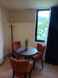a dining room with a table and chairs and a window at Apartmani Nešković Foča in Foča