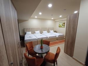 a room with two beds and a table and chairs at Apartmani Nešković Foča in Foča