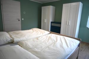 an unmade bed with white sheets in a bedroom at Ferienwohnung Talblick Wilthen in Wilthen