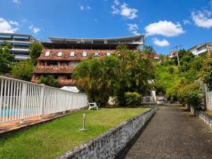 a park in front of a building with a fence at Le Palmier Bleu, Spacious Duplex with Pool in Schœlcher