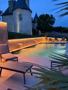 a swimming pool with chairs and a building in the background at La Réserve de Rilhat in Cognat-Lyonne