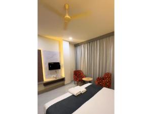 a hotel room with a bed and chairs and a tv at Hotel Arena in Nasīrābād