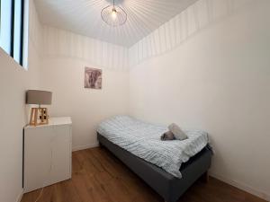 a small bedroom with a bed and a lamp at Appartement La Jungle in Villebois