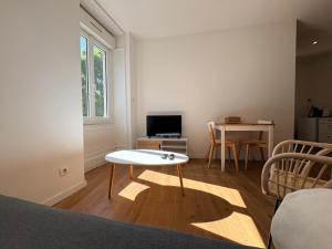 a living room with a table and a small table and a television at Appartement La Jungle in Villebois