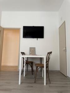 a white table with chairs and a tv on a wall at AuraHouse in Mignanego