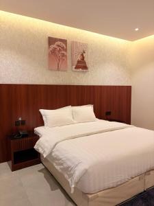 a bedroom with a white bed and two paintings on the wall at اجنحة الفخامة للشقق الفندقية in Taif +27 photos