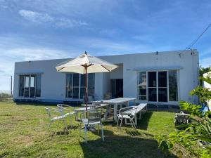 a house with a table and chairs and an umbrella at Beach House Bellissima ! in Yomitan