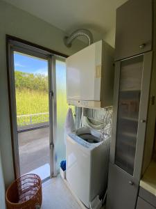 a kitchen with a washing machine and a window at Beach House Bellissima ! in Yomitan