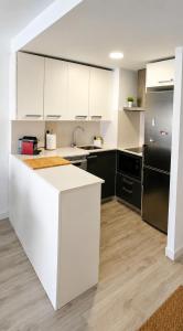 a kitchen with white cabinets and a black refrigerator at Festasol - Apartament Estartit in Torroella de Montgrí