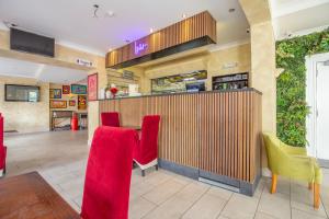 a restaurant with red chairs and a counter at Revado Hotel, Norwich City Centre in Norwich