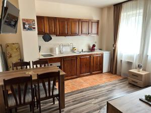 a kitchen with wooden cabinets and a table with chairs at Central apartment in Razlog