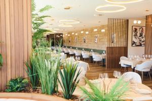 a dining room with tables and chairs and plants at Hotel Aquafalls in Caniçada