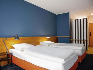 a bedroom with two beds and a blue wall at B&B HOTEL Dresden-Altstadt in Dresden