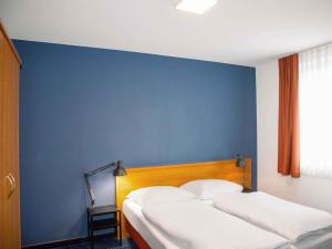 a bedroom with two beds against a blue wall at B&B HOTEL Dresden-Altstadt in Dresden +21 photos