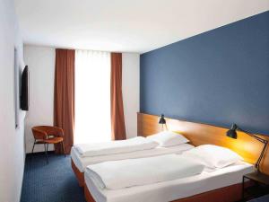 a hotel room with three beds and a blue wall at B&B HOTEL Dresden-Altstadt in Dresden