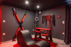 a gym with a treadmill and a chair in a room at L'Interdit, Confort et Sensualité in La Ferté-Gaucher