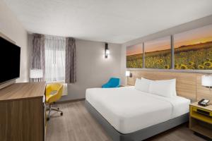 a hotel room with a bed and a flat screen tv at Days Inn by Wyndham Mandan Bismarck Area in Mandan