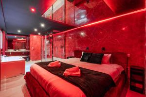 a red bedroom with a bed and a bath tub at L'Interdit, Confort et Sensualité in La Ferté-Gaucher