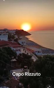 a view of a beach with the sun setting over the ocean at B&B Florida sul mare via faro 30 in Capo Rizzuto