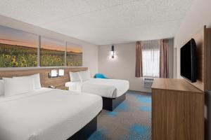 a hotel room with two beds and a flat screen tv at Days Inn by Wyndham Mandan Bismarck Area in Mandan +72 photos
