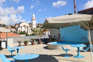 a patio with tables and an umbrella and a pool at Hotel Rezende in Lambari