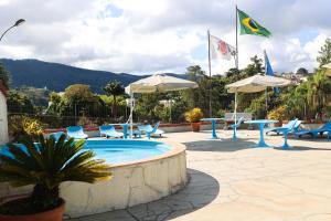a pool with chairs and tables and umbrellas at Hotel Rezende in Lambari