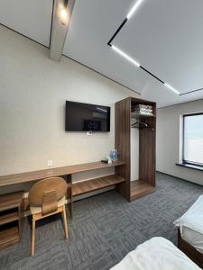 a hotel room with a desk and a tv on the wall at Cube House Osh in Osh