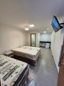 a room with two beds and a flat screen tv at Praia Do Morro Suites Para Grupos Guarapari-es in Guarapari +13 photos