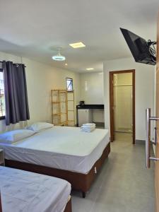 a bedroom with two beds and a television in it at Praia Do Morro Suites Para Grupos Guarapari-es in Guarapari