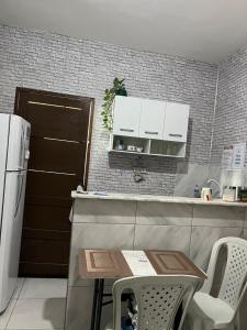 a small kitchen with a table and a refrigerator at Jardim Tropical in Bayeux