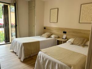 a bedroom with two beds and a window at Hostal Rural Sositana in Castejón de Sos