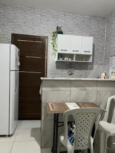 a small kitchen with a table and a refrigerator at Jardim Tropical in Bayeux